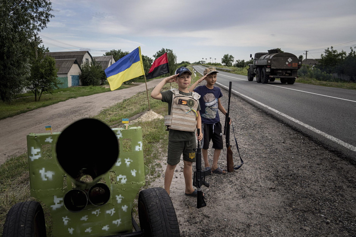 11-річні Максим та Андрій салютують українським бійцям під час гри на саморобному блокпосту на трасі в Харківській області, 20 липня