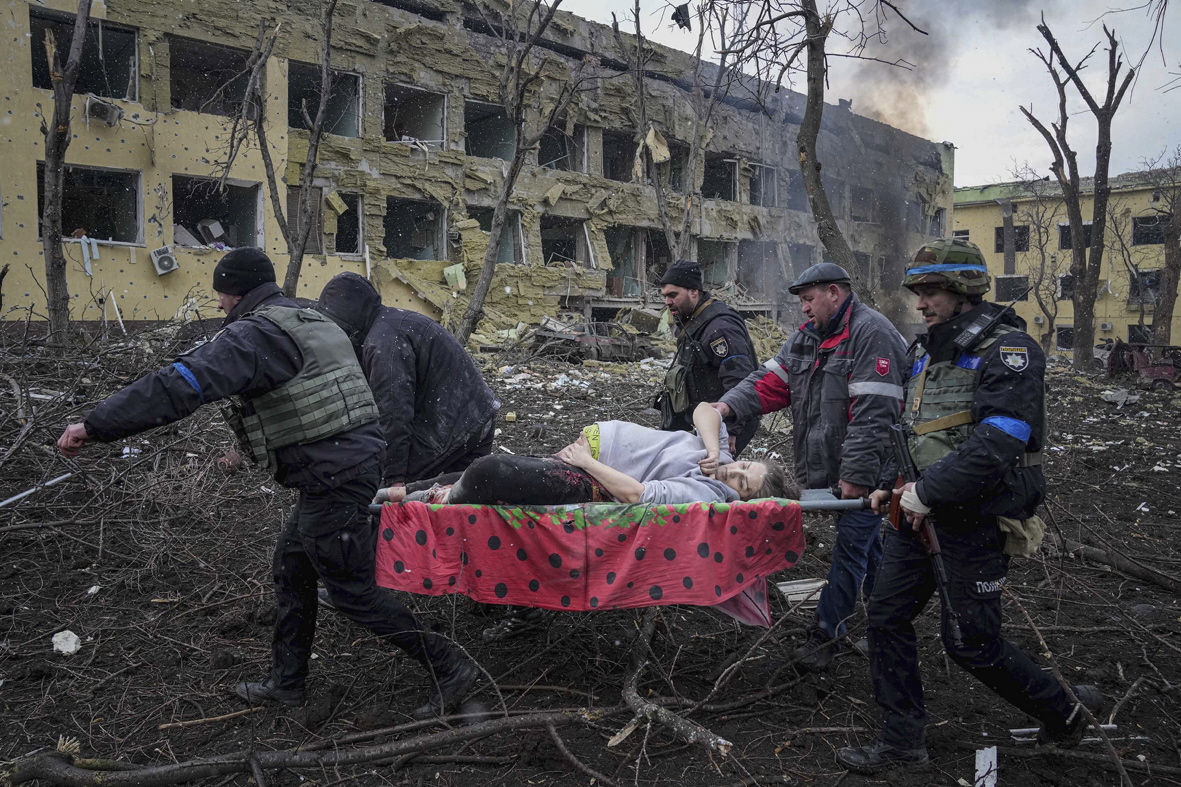 Надзвичайники та волонтери виносять поранену вагітну Ірину Калініну з постраждалого від обстрілу пологового будинку в Маріуполі, 9 березня. Калініна та її дитина не вижили